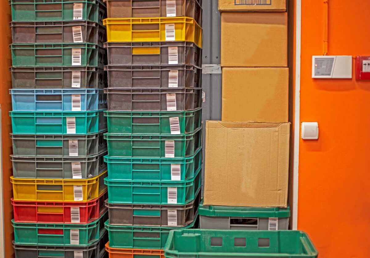 Several large plastic bins and cardboard boxes stacked next to each other in a packed space.