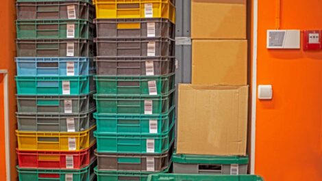 Several large plastic bins and cardboard boxes stacked next to each other in a packed space.